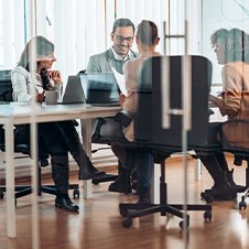Mitarbeitende sitzen an einem Besprechungstisch in einem modernen Büro