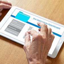 Eine Hand tippt auf ein Tablet, das eine elektronische Patientenakte zeigt