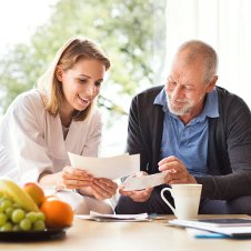 Ärtzin im Gespräch mit einem älteren Mann in häuslicher Umgebung