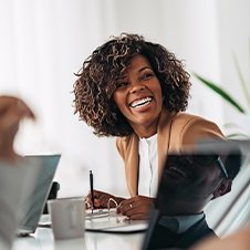 Bildausschnitt Besprechung: lachende Frau über einen Ordner gebeugt